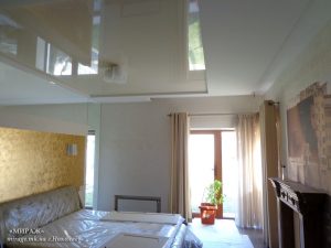 Бежевый лаковый натяжной потолок в спальне